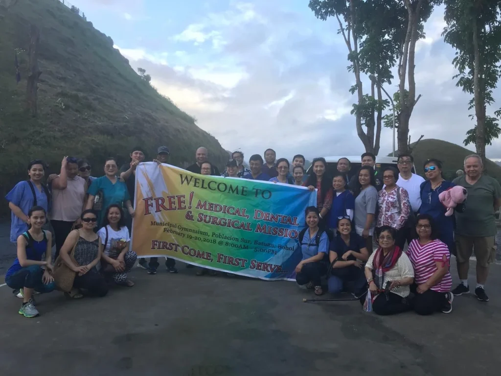 Group of volunteers posing outdoors with a banner during a community event