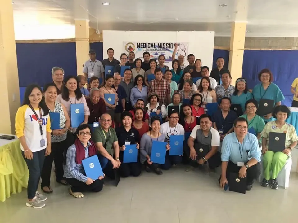 Group of volunteers posing together indoors while holding certificates after a community program